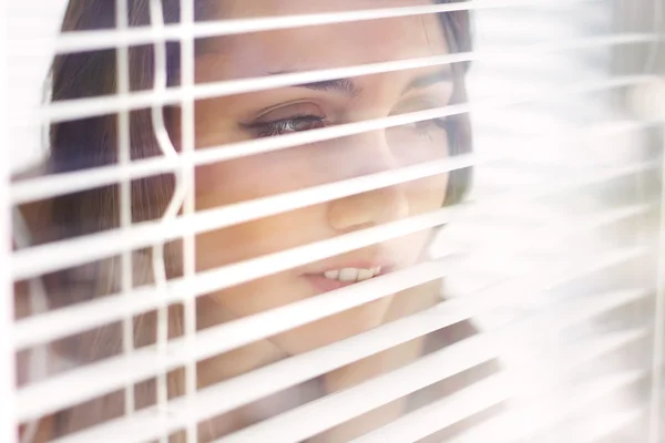 Attractive girl looks out blinds