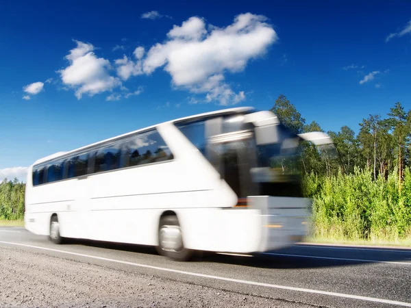White bus speeding on highway, blurred in motion