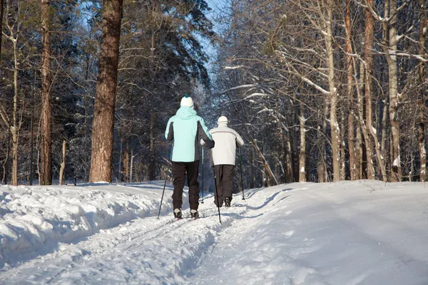 Man and woman walk on ski in winter forest