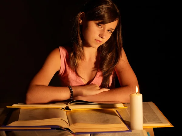 Girl reading book with candle.