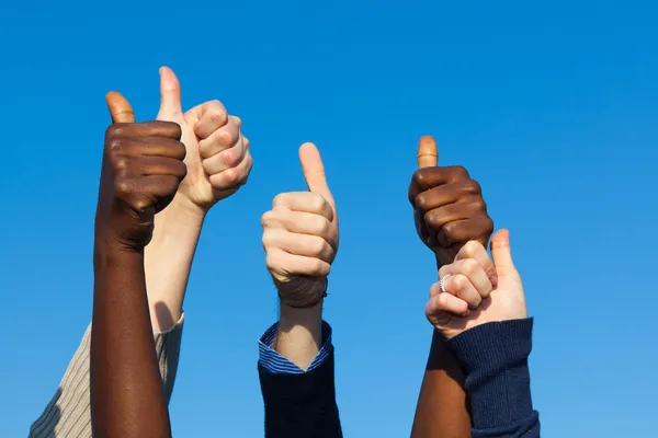 Multiracial Thumbs Up Against Blue Sky