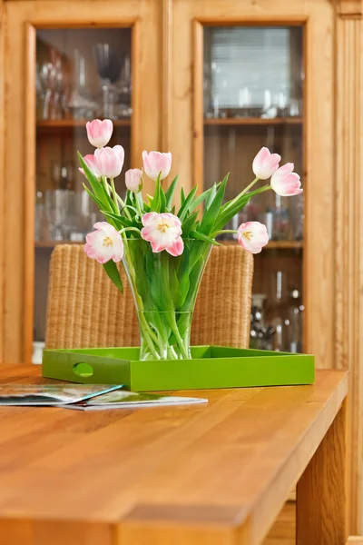Bouquet of pink tulips flowers in glass vase on wooden table