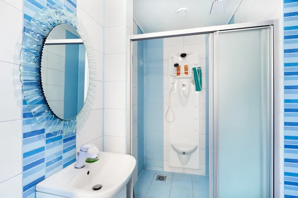 Modern blue bathroom interior with round mirror and shower cubic