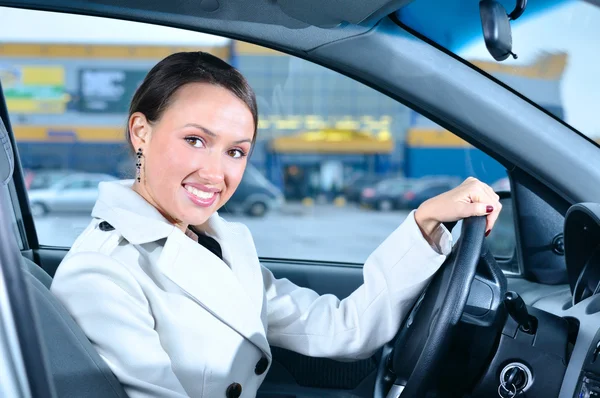 Happy business woman in a car is looking at camera