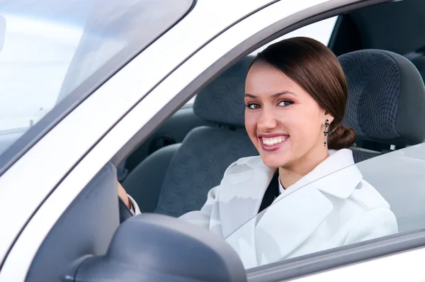Happy business woman in a car is looking at camera