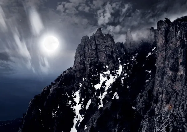 Moonlit night and clouds on night sky in the mountains