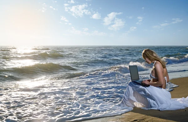 Blond girl using laptop on sea