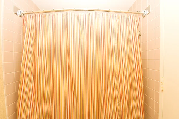 Bath tub behind striped colourful curtain