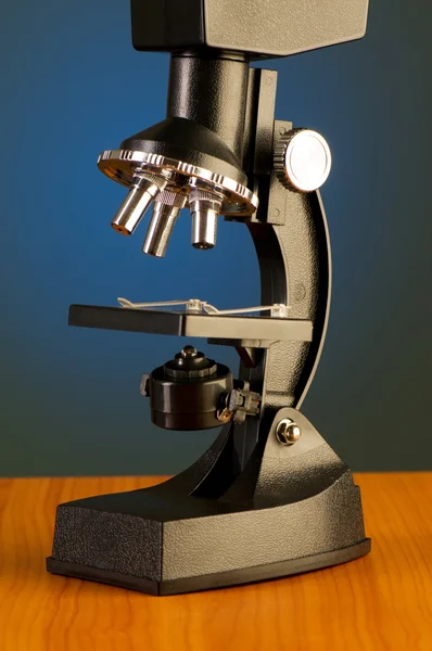 Microscope against blue gradient background