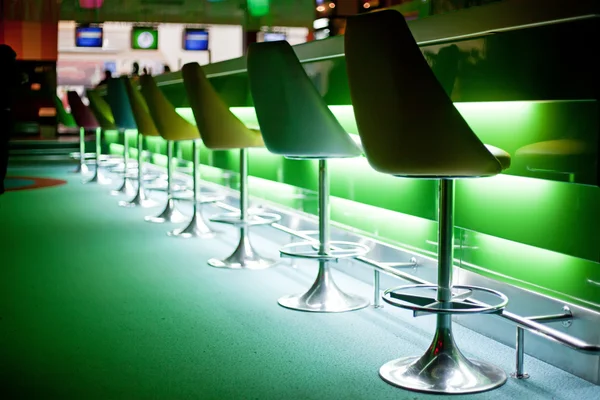 Chairs in bar with green lights