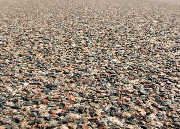 Uneven asphalt road with stones