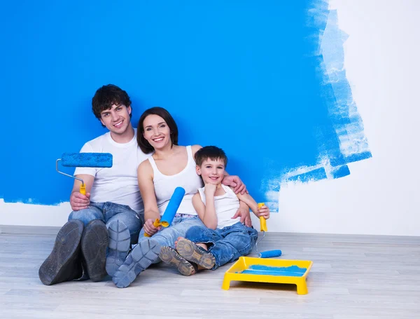 Smiling family with paintbrush near the wall