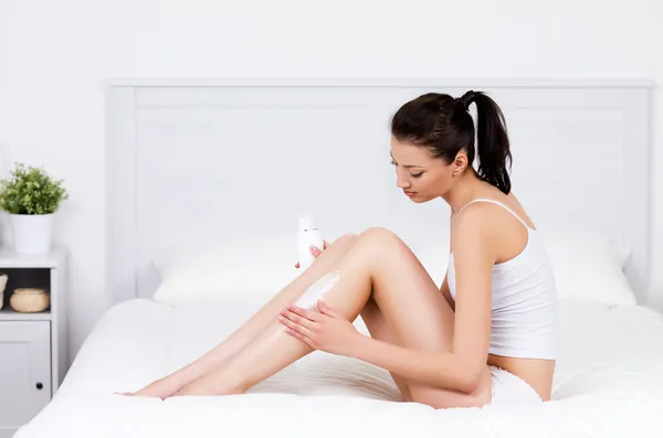 Woman caring about her legs with lotion