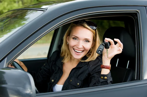 Beautiful happy woman in the new car with keys