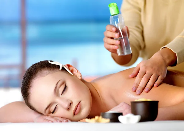 Woman getting massage with cosmetic oil in spa salon