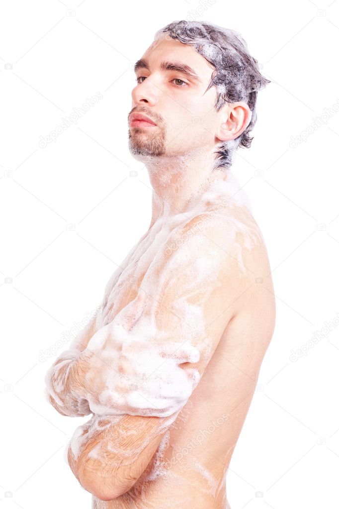Young naked man taking a shower in the foam with a beautiful body isolated