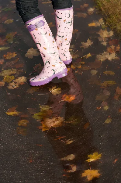 Woman rainboots in the autumn puddle