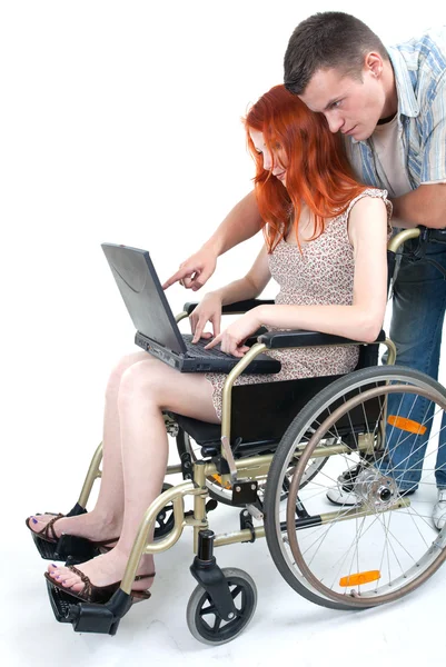 Man, woman keeping laptop on wheelchair