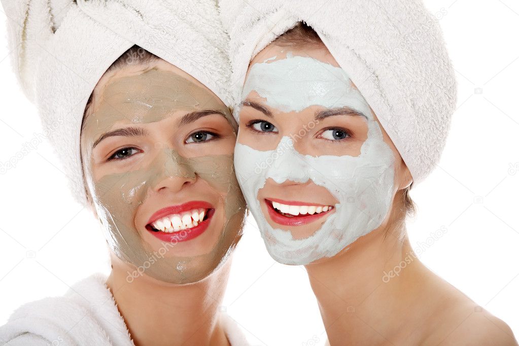 Young happy women with facial clay mask isolated on white