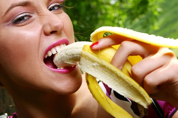 Beautiful young woman eating banana