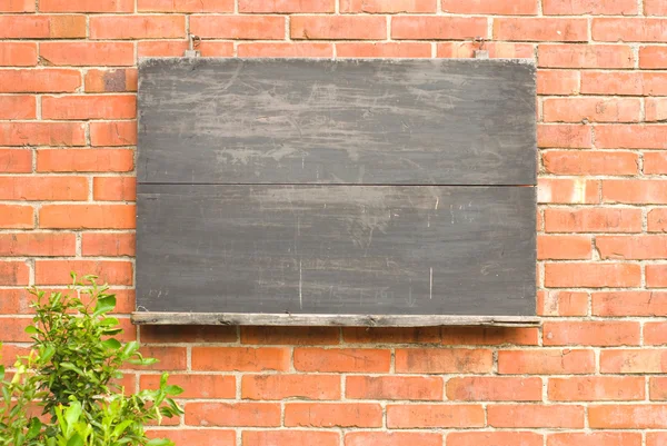 Aged blackboard on red brick wall.