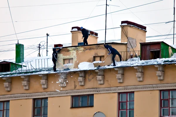 Russia. Petersburg. Workers clean snow and icicles from a house roof