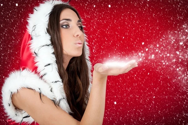 Attractive girl in Christmas costume blowing snow form hand