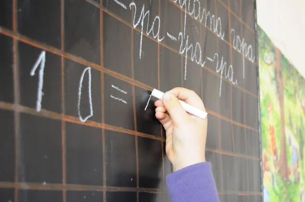 Child hand writing on blackboard
