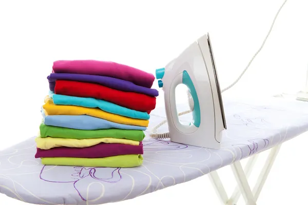 Pile of laundry and iron on ironing board