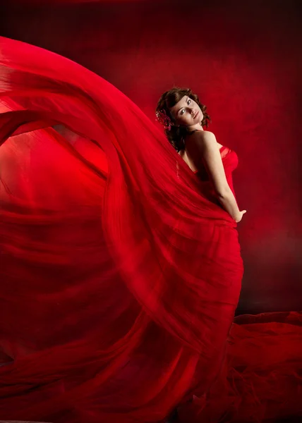 Beautiful woman in red flying waving dress.