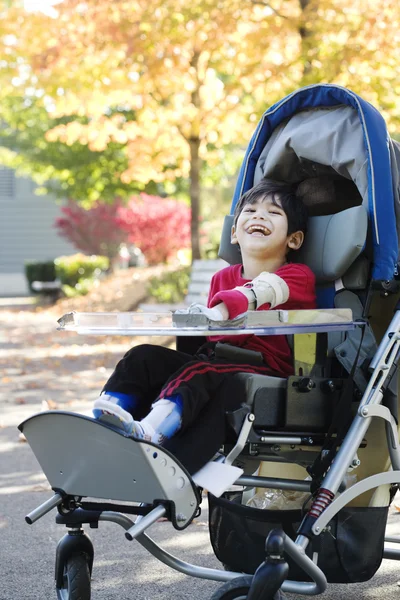 Disabled boy in medical stroller outdoors
