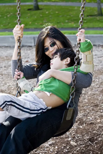 Mother swinging with her disabled son