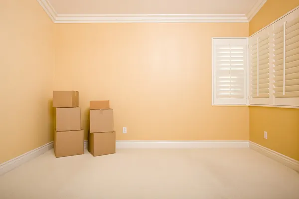 Moving Boxes in Empty Room with Copy Space on Wall