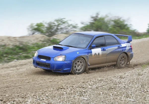 Blue racing rally car on wet gravel road