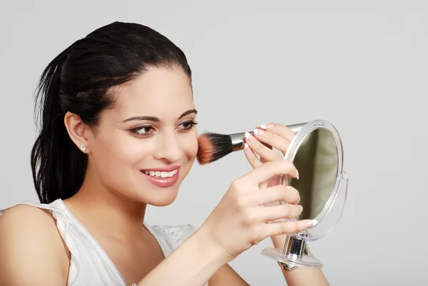 Hispanic woman putting on her makeup