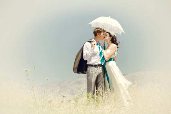 The groom and the bride kiss under summer the hot sun in mountai