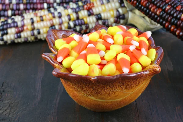 A bowl of candy corn on rustic wooden table