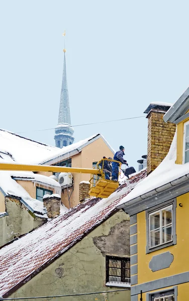 Workers clean snow from a house roof