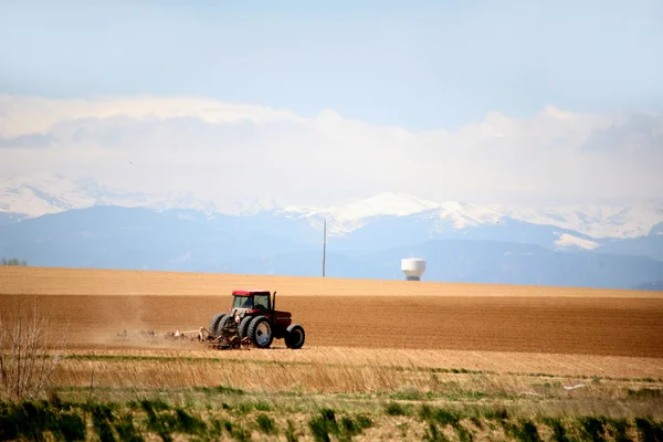 Tractor plowing a field with mountains in the background