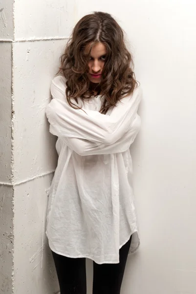 Young insane woman with straitjacket standing looking at camera