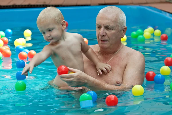 Grandfather and grandson having fun in the pool.