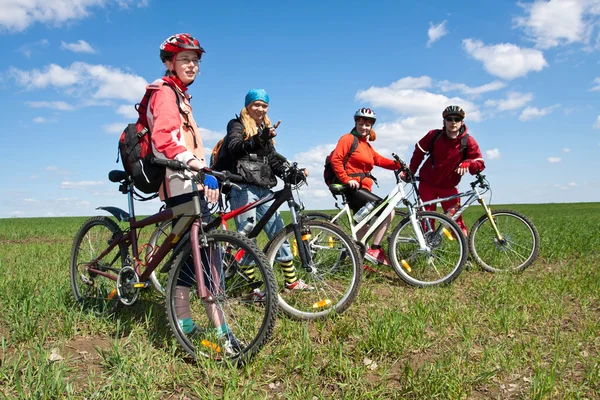 A group of four adults on bicycles in the countryside.