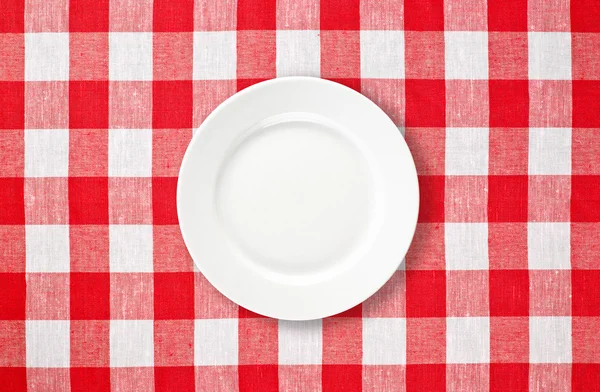 Orange plate on red checked tablecloth
