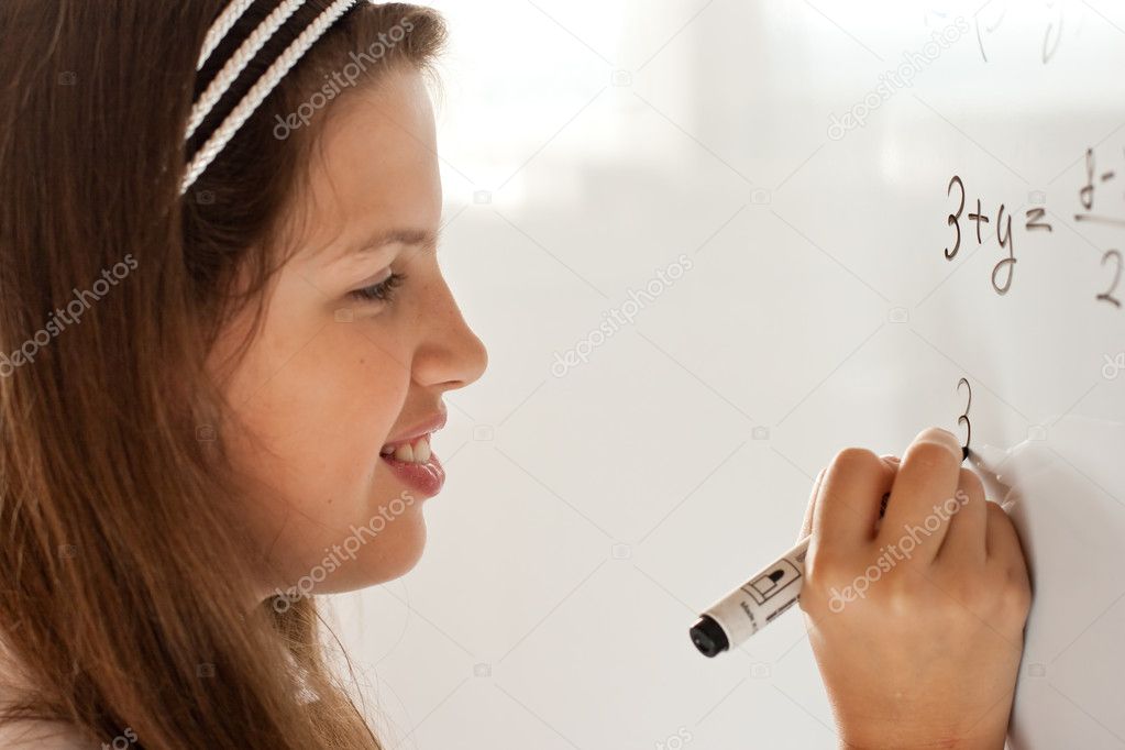 Cute preteen schoolgirl writing letter on whiteboard studiously