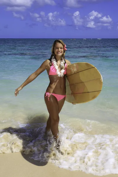 Teenager walking her surfboard from the ocean