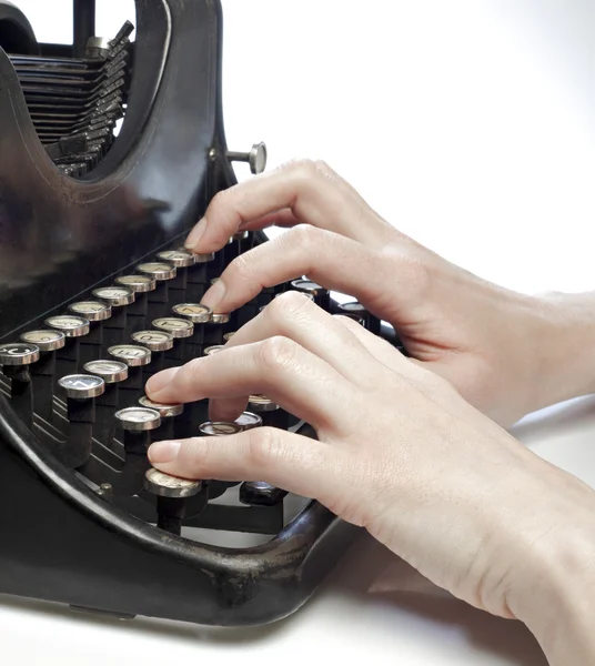 Hands typing on an old style typewriter.