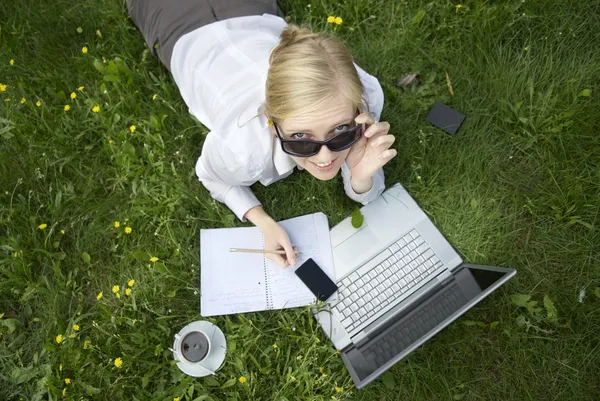 Young blonde woman working outside on computer