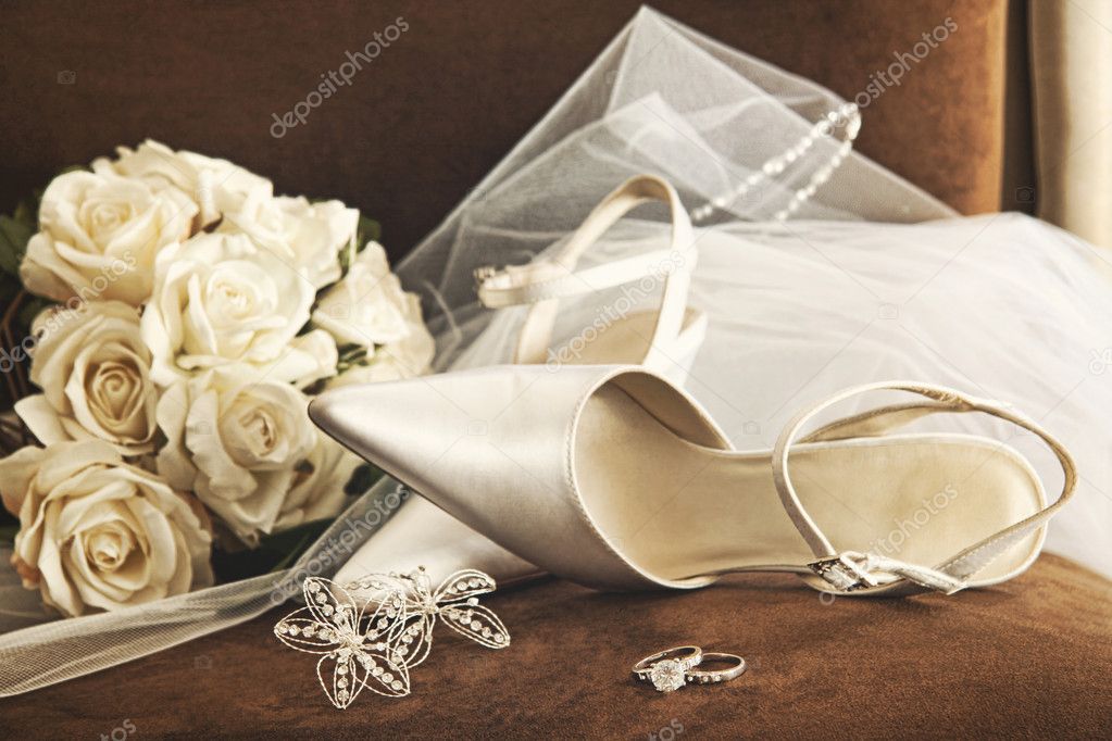 Wedding shoes with bouquet of white roses and ring on chair