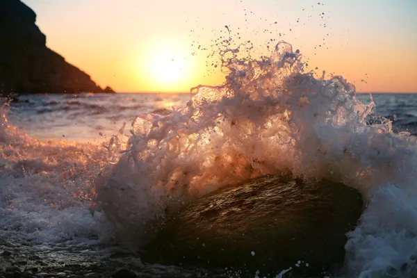 At sunrise, waves crash on the stone