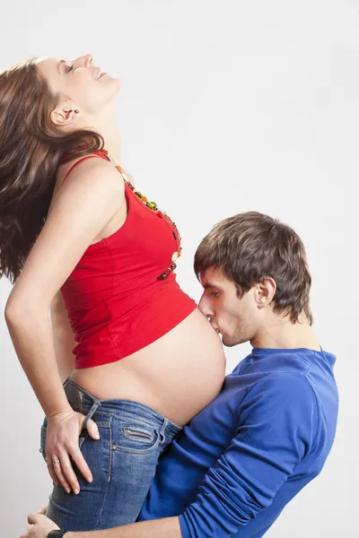 Man kissing his pregnant smiling wife at belly